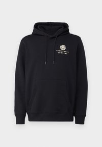 Musta huppari, jossa on kengurupukko, nauhallinen huppu ja kerma-logo, jossa lukee "SKATEBOARD COMPANY" rinnassa. Pehmeä kankaan tekstuuri.