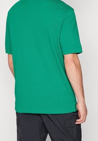 Grön kortärmad t-shirt i mjuk bomull med avslappnad passform. Har en rak nederkant och sidoflikar för ökad komfort.