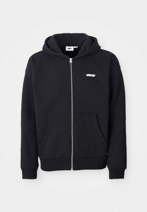 Schwarze Zip-Up-Hoodie aus einem Baumwollmischgewebe. Mit einer Vordertasche, gerippten Manschetten und einem kleinen weißen "obey"-Logo auf der Brust.
