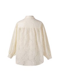 Ivoorkleurige kanten blouse met een kraag, lange mouwen en een loszittende pasvorm. Voorzien van een gestructureerd bloemenpatroon en manchetten met knopen.