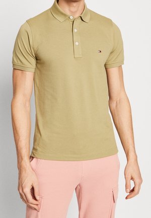 Koszulka polo w kolorze khaki wykonana z bawełny, z klasycznym kołnierzykiem, plisą na trzy guziki oraz małym logo na lewej piersi.