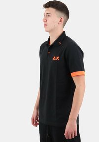 Maglietta polo nera con inserti arancioni sul colletto e sulle maniche. Presenta un logo sul petto e un design elegante e minimal.