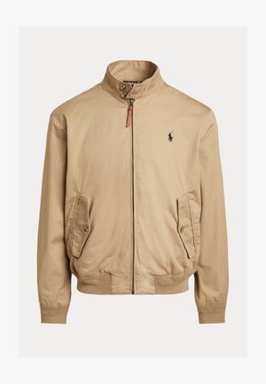 Beige bomberjakke laget av glatt stoff. Har stående krage, to sidelommer, ribbede mansjetter og en liten logo på brystet.