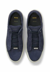 Pair of navy blue BOSS suede sneakers with black laces, white soles, and gold "BOSS" branding inside and on lace tags.