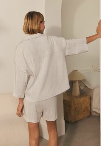 Lichtgrijze, geweven loungewear-set met een losse, korte mouw top en bijpassende shorts met een subtiele textuur en stijlvolle snit.