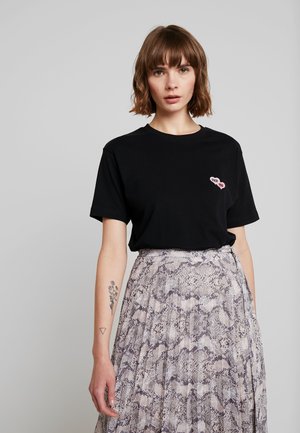 Black cotton t-shirt with short sleeves and a pink heart graphic that has text. Paired with a patterned, pleated, snakeskin print skirt.