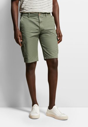 Khaki Cargo-Shorts mit lockerer Passform, Front- und Seitentaschen sowie einem Knopfverschluss. Getragen mit weißen Sneakers und einem gestreiften Hemd.