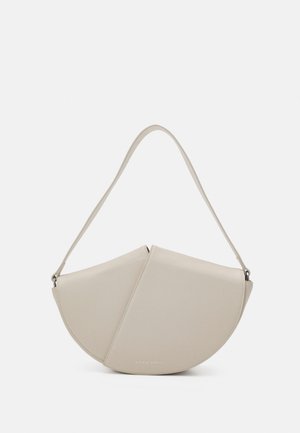 Sac à main en cuir beige avec une forme unique en demi-lune, texture lisse et une fine bandoulière. Présente un logo embossé discret.