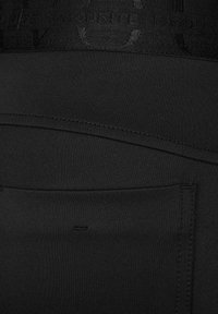 Musta legginsit, joissa on sileä, venyvä kangas, leveä vyötärönauha logotapauksella ja takataskusuunnittelu.