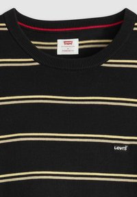 Svart stickad tröja med horisontell randig design i beige och krämfärg. Ribbad halsringning och liten Levi's-logotyp på framsidan. Standard passform.