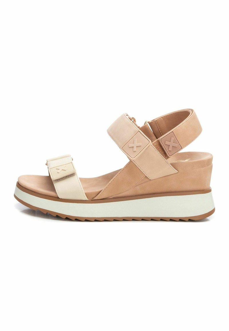 Sandalias de cuña beige con dos correas ajustables, parte superior de cuero suave y suela texturizada. La suela tiene una banda blanca de contraste.