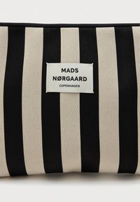 Czarna i kremowa torba w paski o teksturowanej powierzchni, z naszytą metką z napisem "MADS NØRGAARD COPENHAGEN" w czarnym kolorze.