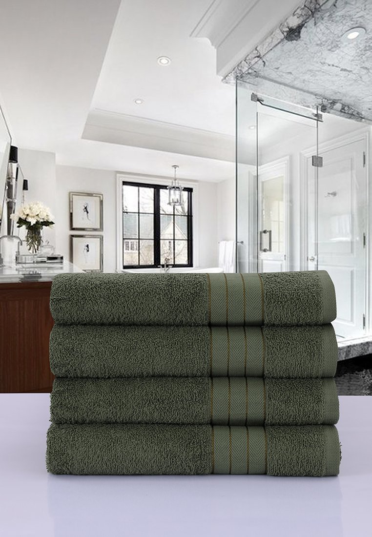 Juego de cinco toallas verde oscuro apiladas de manera ordenada. Textura suave con franjas de acento horizontales. Ambientación de baño con elementos de diseño moderno visibles.