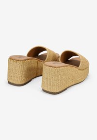 Sandalias de plataforma de paja trenzada con punta cerrada, parte superior curva y un tacón bloque sustancial, con un color beige natural y superficie texturizada.