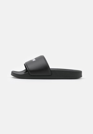 Sort slip-on slide sandal med bred rem og formet fodseng, vist fra siden på ensfarvet baggrund.