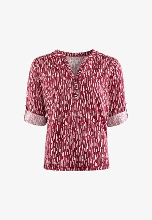 Rote Kurzarmbluse mit V-Ausschnitt und Knopfdetails, versehen mit einem geometrischen weißen Muster und kontrastierenden Ärmelabschlüssen. Weiche Stoffstruktur.