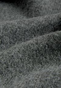 Grå vævet stof med en tekstureret overflade, der fremviser et blødt, fuzzy udseende og subtil dybde skabt af overlappende folder.