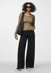 Svarte vide jeans, khaki ribbet langermet topp med knapper, svart tote bag og mørke solbriller. Glatte teksturer, avslappet stil.