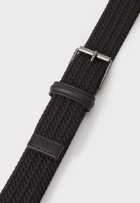 Cinturón tejido negro con un tejido texturizado, un lazo de cuero y una hebilla de metal para un cierre seguro. Diseño notablemente elástico.