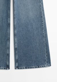 Jeans mit weitem Bein aus hellblauem Denim, mit strukturierter Stoffqualität, ausgefranstem Saum und sichtbaren Nahtdetails.