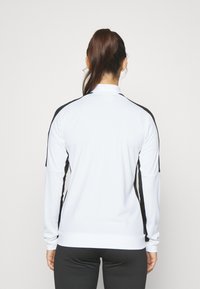 Lange mouwen sporttop in het wit met zwarte zijde-accenten, met een hoge kraag, een gladde textuur en een losse pasvorm.