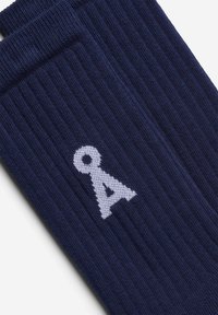 Marineblaue, gerippte Socken mit weißem, gestricktem Logodetail. Verfügen über eine strukturierte Oberfläche und eine bequeme Manschette am oberen Rand.