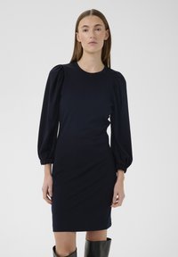 Rochie conică bleumarin cu mâneci bufante și decolteu rotund, realizată dintr-un material neted. Are o croială până la genunchi, cu cusături laterale subtile.