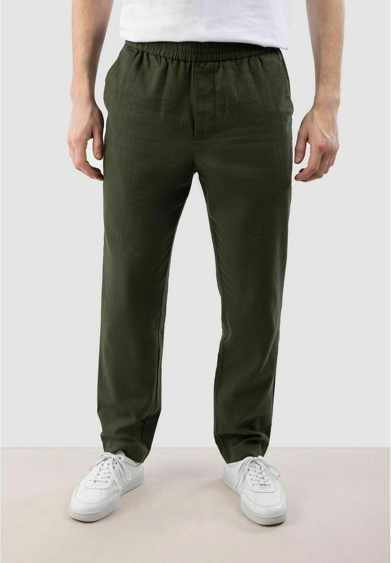 Groene linnen broek met een elastische tailleband, heeft een ontspannen pasvorm en zijzakken, gecombineerd met witte sneakers.