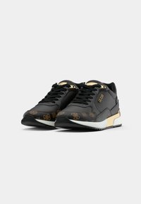 Zapatillas deportivas negras con acentos dorados, patrones texturizados en la punta, un cuello acolchado y una suela blanca. Diseñadas con una forma elegante y moderna.
