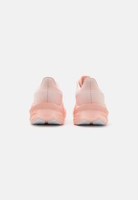 Light pink athletic shoes with a textured upper, cushioned sole, and contrasting white accents at the heel and outsole.