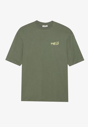 Camiseta de algodón verde oliva de manga corta, con cuello redondo y texto "PARIS" en un tono más claro en el lado izquierdo del pecho.