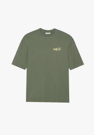 Olijf groene katoenen T-shirt met korte mouwen, ronde halslijn en de tekst "PARIS" in een lichtere tint op de linkerkant van de borst.