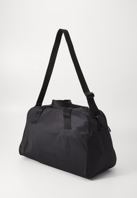 Black duffle bag made of smooth material, featuring dual handles, a removable shoulder strap, and a zippered closure.