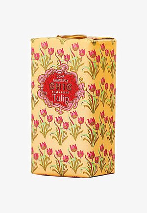 Gelbe Seifenverpackung mit einem floralen Muster aus pinkfarbenen Tulpen und grünen Stängeln, versehen mit einem roten Etikett, auf dem "Chic" und "Tulpe" steht.