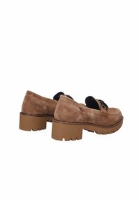 Mocassini in suede marrone con una suola spessa e texture. Presentano un accento in pizzo nero e un piccolo logo rosso sul lato. Design con punta arrotondata.