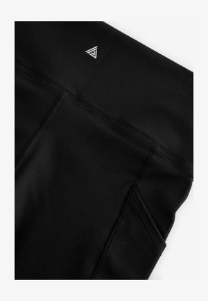 Mustad spordipüksid siledapinnalise tekstuuriga, millel on väike kolmnurkne logo ja küljetasku. Õmblused on nähtavad mööda saumu.