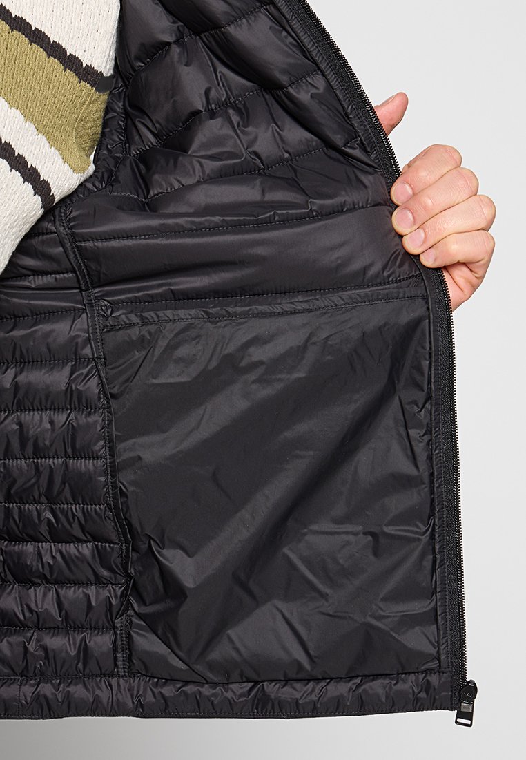 Interno di una giacca a vento nera con texture trapuntata, caratterizzata da una zip liscia e da una tasca interna sul lato sinistro.