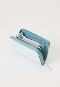 Calvin Klein gaiši zils rāvējslēdzēja maks, izgatavots no gludas ādas, ar kartes nodalījumiem un sudraba rāvējslēdzēja cilpu, ar mazu logotipu iekšpusē.