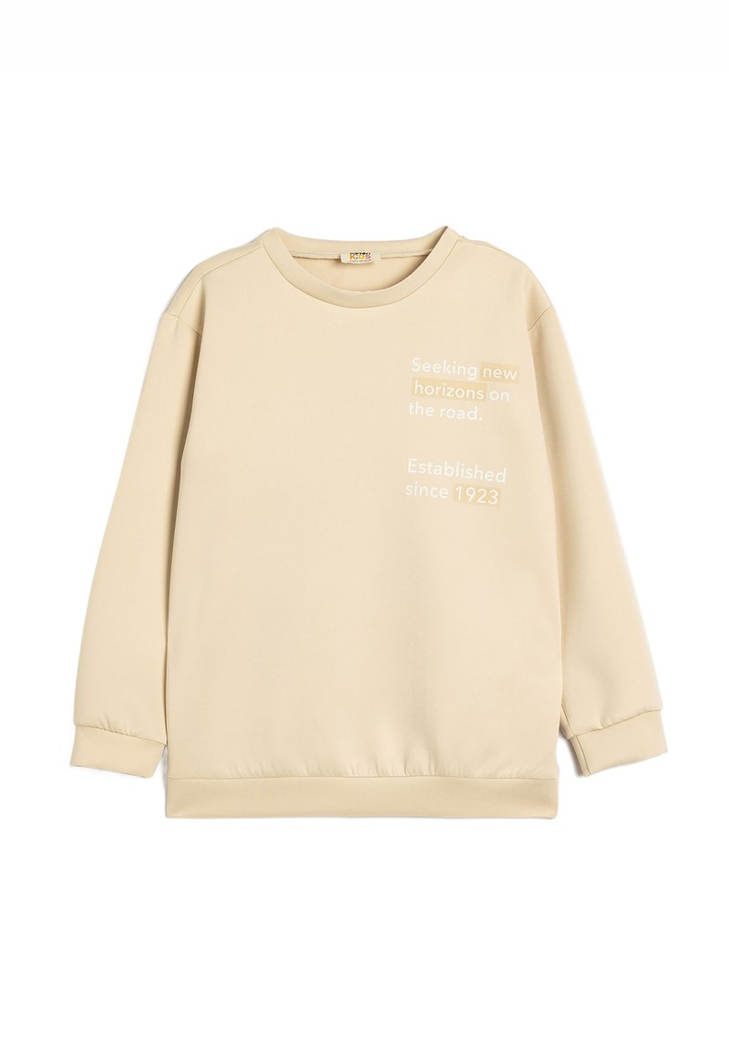 Beige sweatshirt med rund halsudskæring, lange ærmer og elastiske manchetter. Tekstgrafik på forsiden: "Søger nye horisonter på vejen."