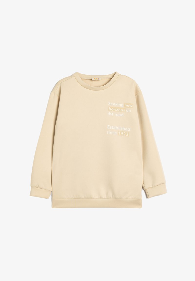 Beige sweatshirt med rund halsudskæring, lange ærmer og elastiske manchetter. Tekstgrafik på forsiden: "Søger nye horisonter på vejen."