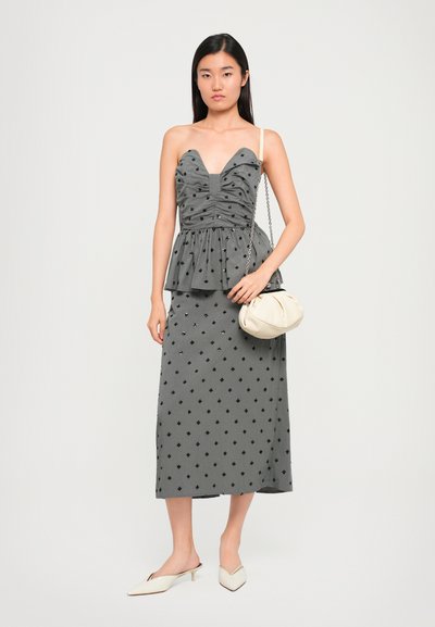 Γκρι φόρεμα με peplum και φάσες στο μπούστο, διακοσμημένο με μαύρα διαμαντένια σχέδια, συνδυασμένο με μπεζ μούλες και μια κρεμ τσάντα με αλυσίδα.