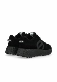 Black sneakers made of suede with a textured black sole. Features a circular design element and fuzzy collar. Includes branding on the heel.