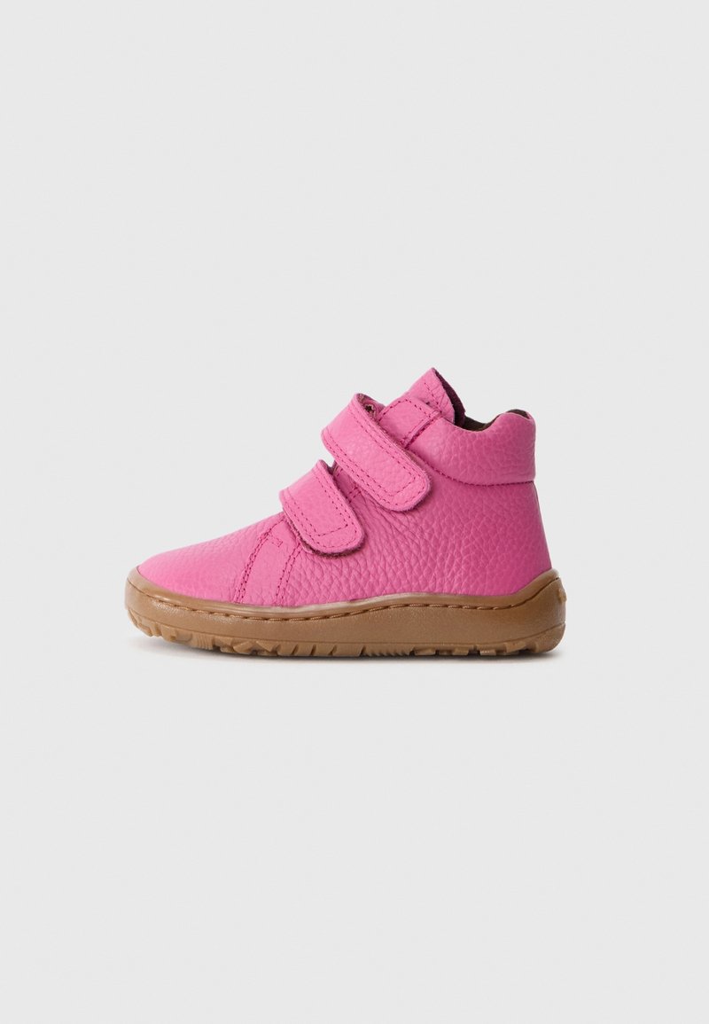 Chaussure montante rose pour enfants en cuir texturé, avec deux bandes auto-agrippantes et une semelle en caoutchouc marron sur fond gris.