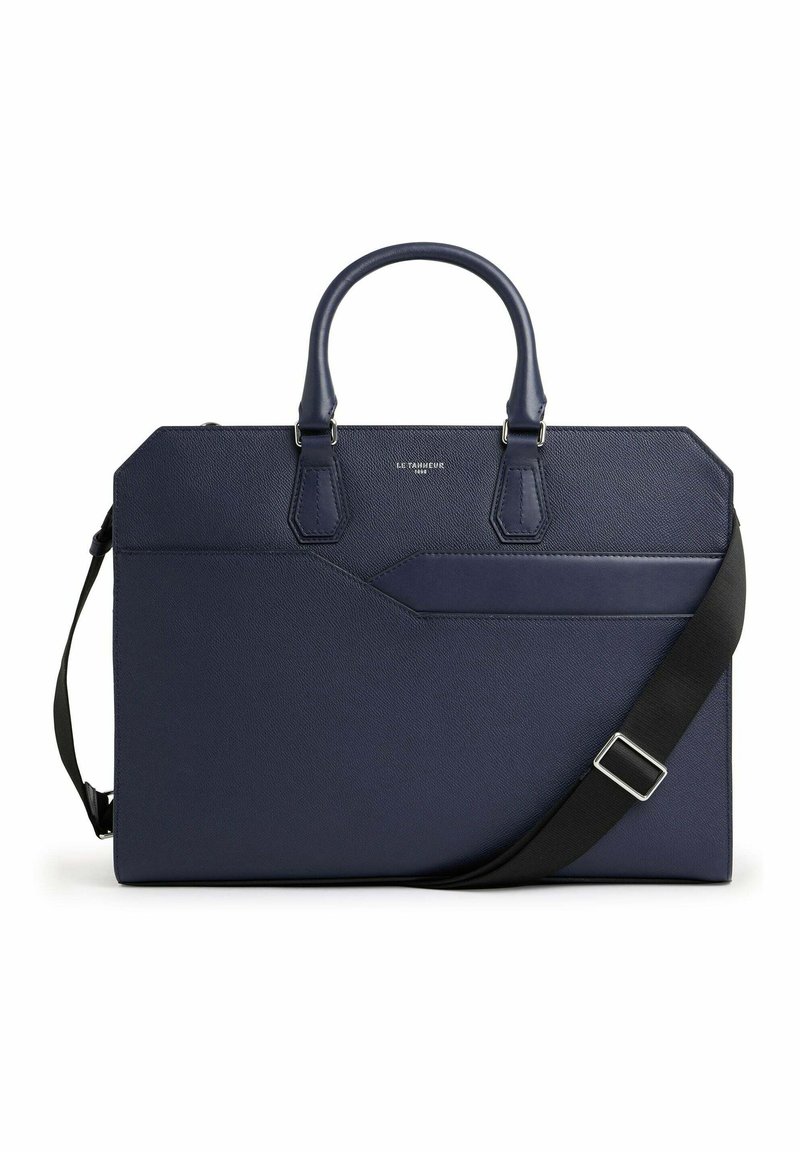 Bolso de cuero texturizado en color navy con asas dobles y una correa negra desmontable. Presenta un bolsillo frontal y elementos de diseño geométrico.