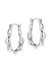 Srebrne kolczyki w formie obręczy z falistym, rzeźbiarskim wzorem. Gładka, błyszcząca struktura o nietypowym, płynącym kształcie oraz bezpiecznym mechanizmie zapięcia.