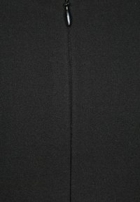 Tissu côtelé noir avec un design de fermeture éclair centré. Présente une texture mate lisse et un petit détail de tirette en haut.