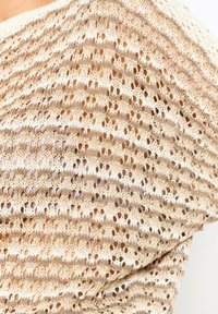 Luftiges, kurzärmeliges Oberteil in Beige mit goldenen Fadenakzenten. Es weist eine offene Webart und ein gestreiftes Muster mit einer strukturierten Oberfläche auf.