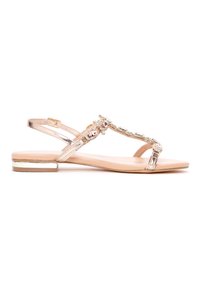 Sandalia con suela plana, parte superior de charol nude, diseño de tiras en forma de T, adornada con gemas transparentes y rosas, y detalles metálicos dorados en el tacón.