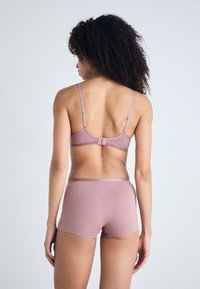 Pink wireless bra and matching boyshorts made of soft fabric, featuring adjustable straps and a hook-and-eye closure for a secure fit.