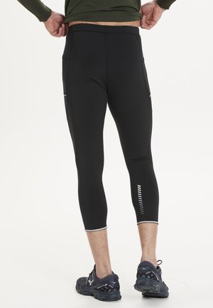 Black compression leggings with a fitted design, featuring two side pockets and reflective accents along the calves. Smooth texture.